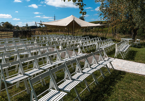 Outdoor ceremony set up with stretch canopy in background